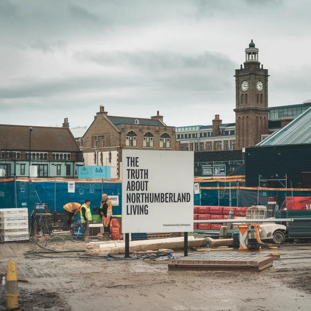 blog post for northumberland living , image is of a london building site in centre is white sign with black text reading the truth about northumberland living